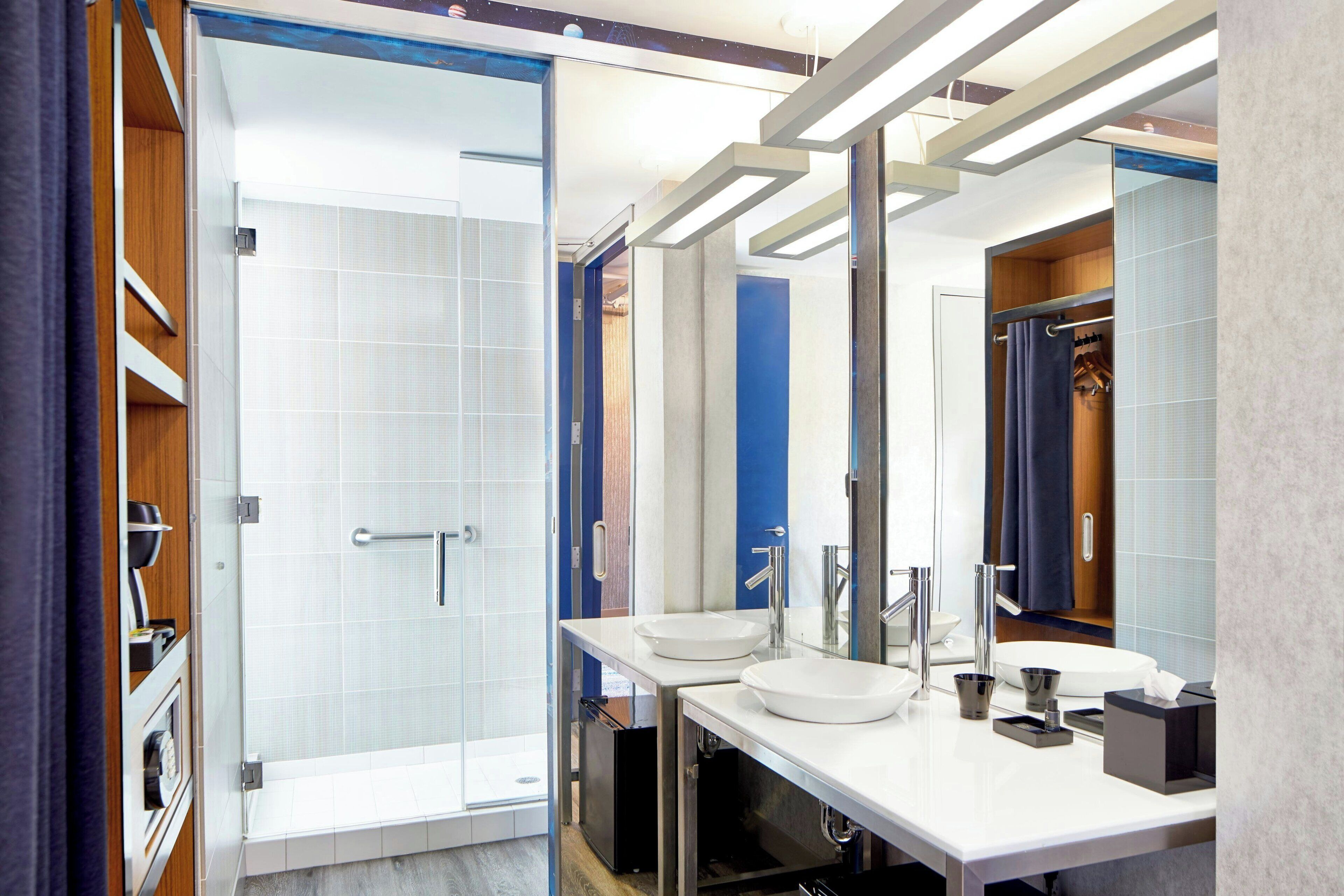 A modern bathroom with a glass shower enclosure, two sinks, and a large mirror.