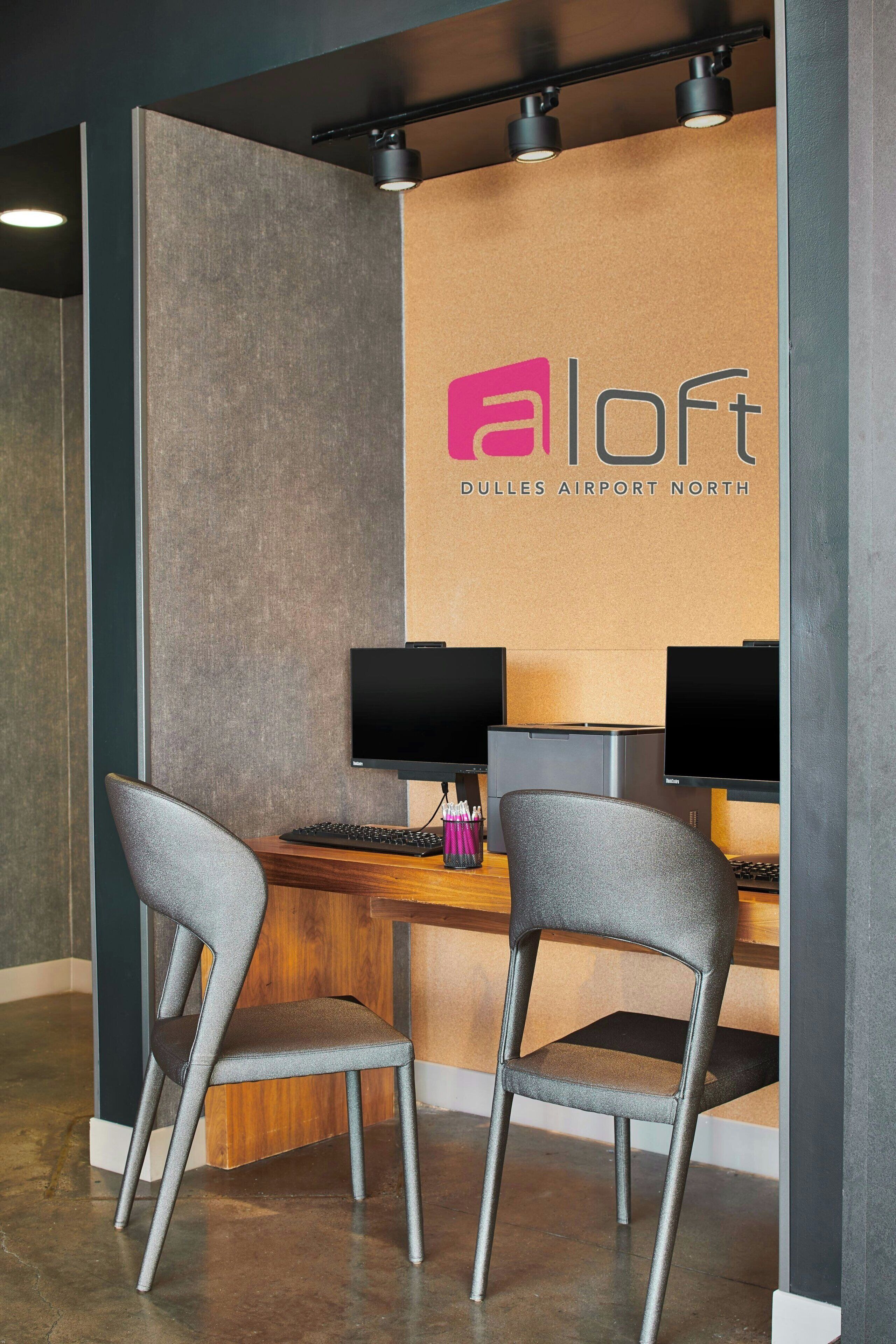A modern workspace with two computer monitors, a keyboard, and two grey chairs.