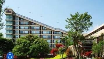 Een modern hotel met een meerlaags gebouw, een aangelegde tuin en een heldere lucht.