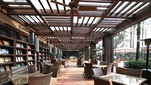 A covered outdoor seating area with wicker furniture and bookshelves. - Howard Johnson Conference Resort Chengdu (Chengdu)