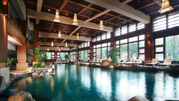 A large indoor swimming pool with natural rock formations and lounge chairs. - Howard Johnson Conference Resort Chengdu (Chengdu)