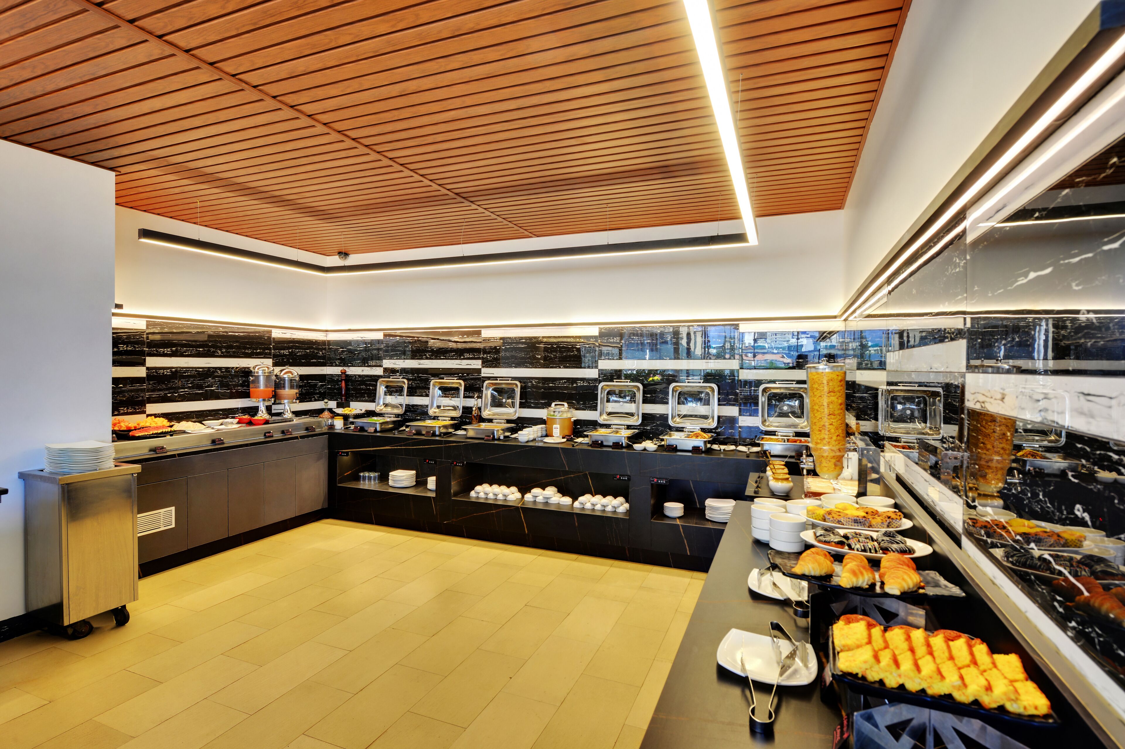 A modern buffet with a variety of food items, a wooden ceiling, and a city view.