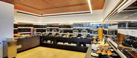 A modern buffet with a variety of food items, a wooden ceiling, and a city view.