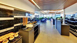 Un espace moderne dédié au petit-déjeuner, doté de plans de travail en marbre, d’un coin café et de sièges pour les clients.