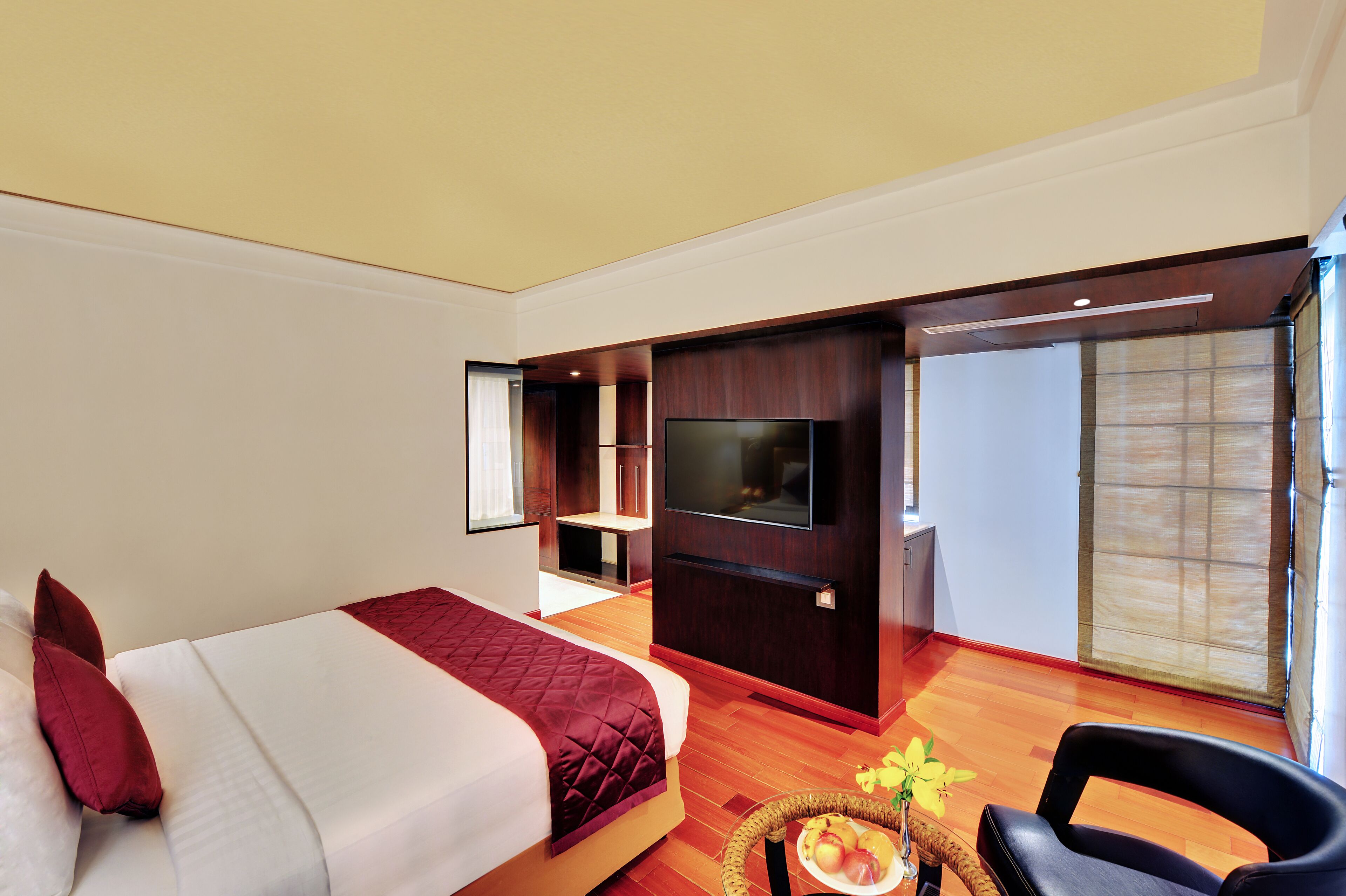 Ein Hotelzimmer mit Bett, Fernseher, Sitzecke und einer Schiebetür zum Balkon.