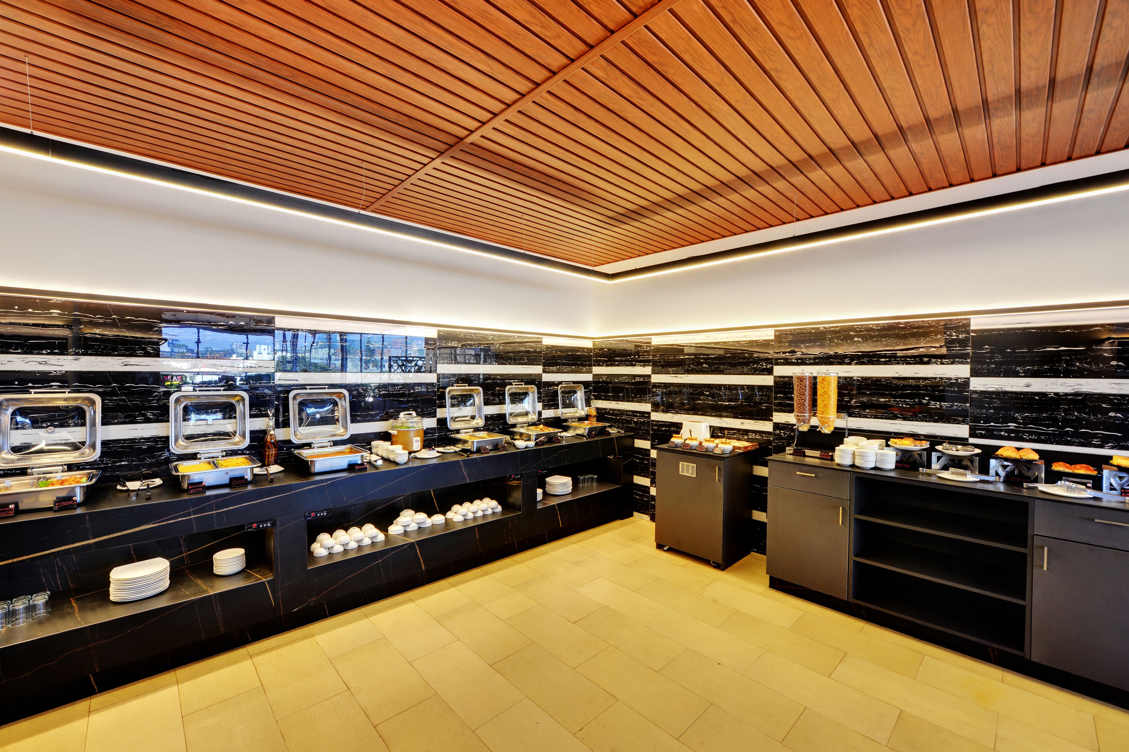 A modern kitchen with black marble countertops, stainless steel appliances, and a wooden ceiling.