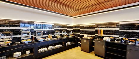 A modern kitchen with black marble countertops, stainless steel appliances, and a wooden ceiling.