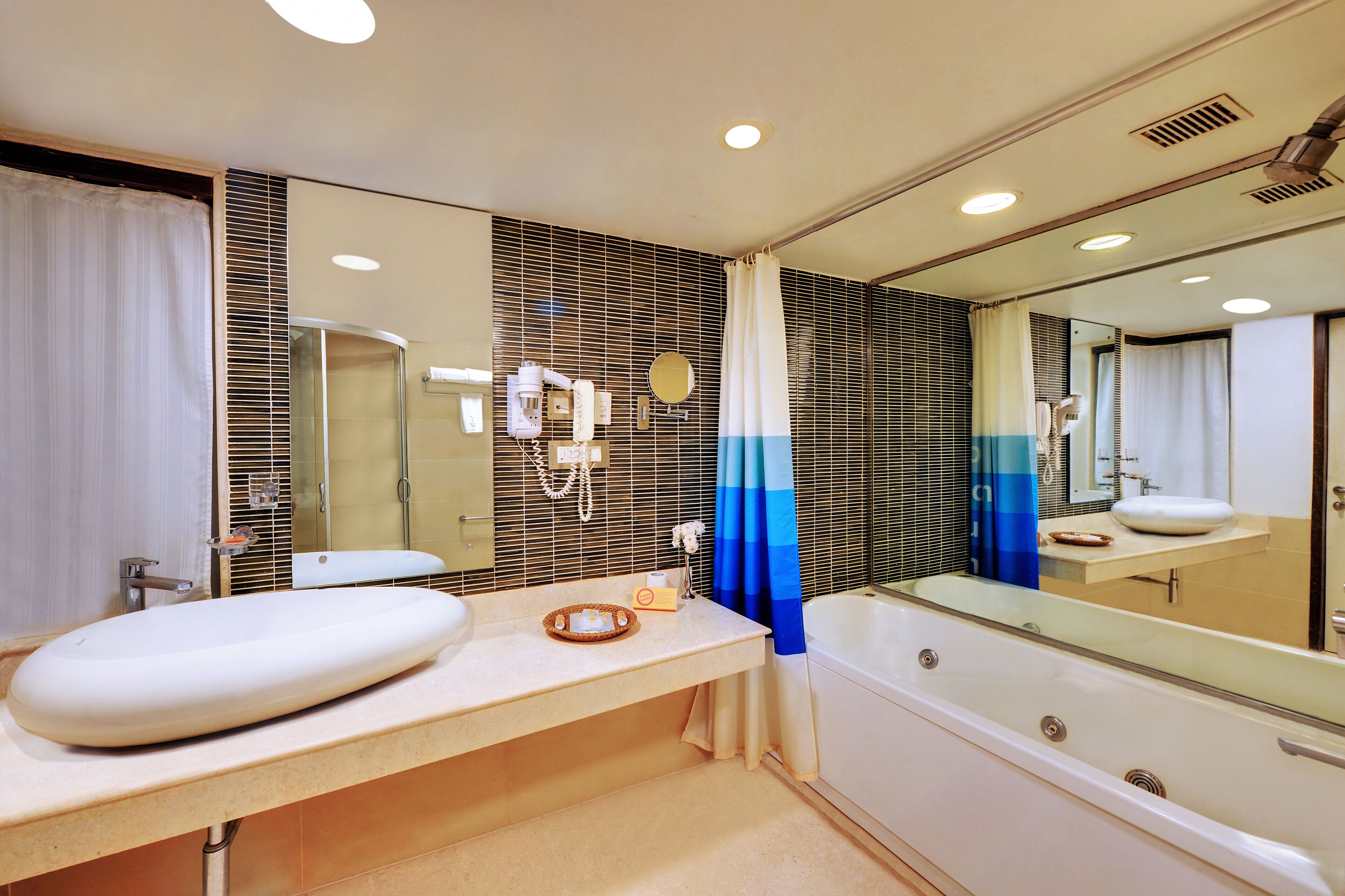 A modern bathroom with a large mirror, a bathtub, and a sink.