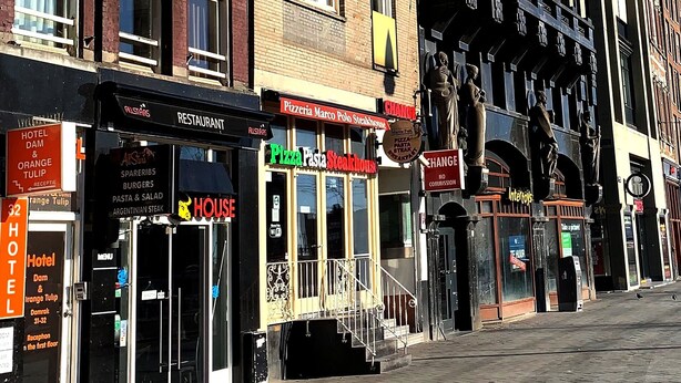 Eine Reihe mehrstöckiger Gebäude mit verschiedenen Geschäften, darunter ein Restaurant und eine Pizzeria.
