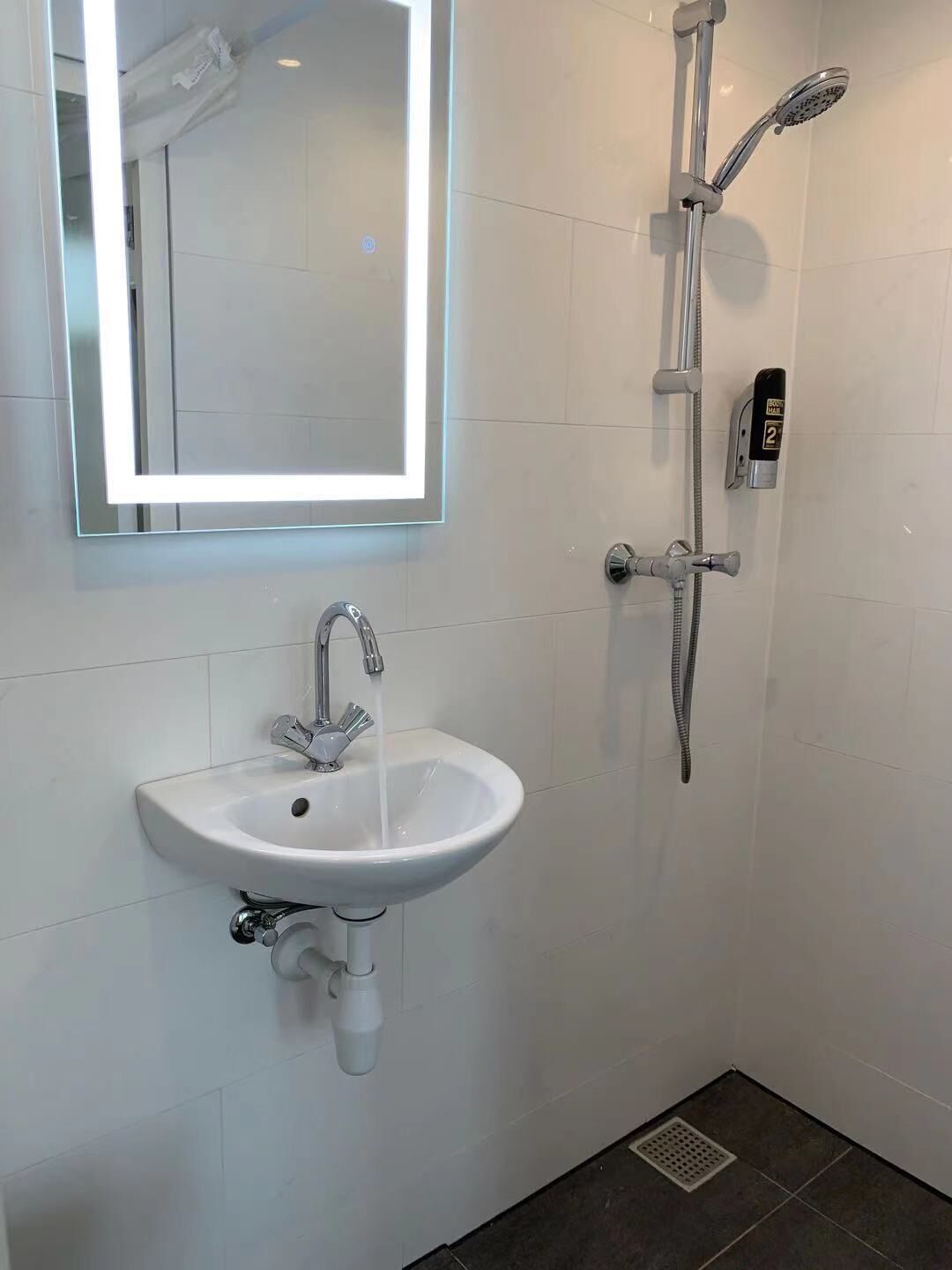 A modern bathroom with a white sink, a large mirror, and a shower with a handheld showerhead.
