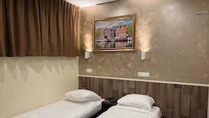 Ein Hotelzimmer mit zwei Einzelbetten, einem Stadtbildgemälde und einem hölzernen Kopfteil.