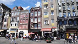Eine Straße mit historischen Gebäuden, einem Café und einem Glockenturm.
