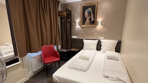 Ein Hotelzimmer mit einem Bett, einem roten Sessel, einem Schreibtisch und einem Gemälde an der Wand.
