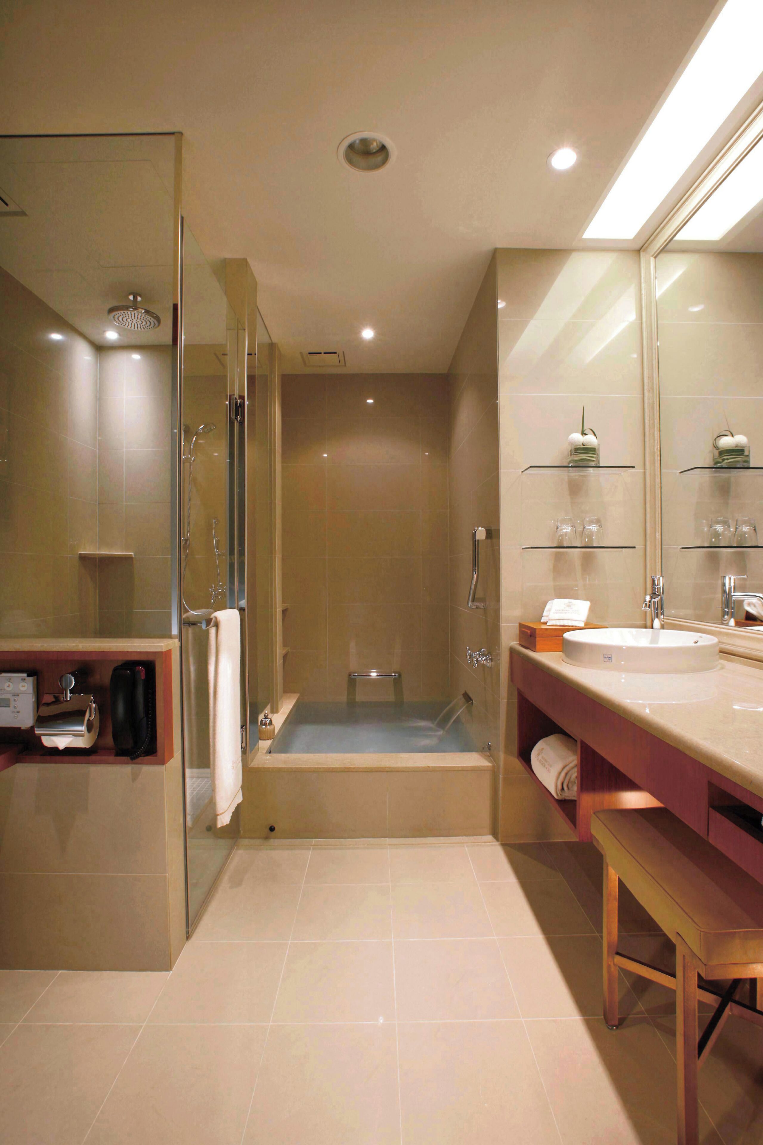 A modern bathroom with a glass-enclosed shower, a large mirror, and a vanity with a sink and countertop.
