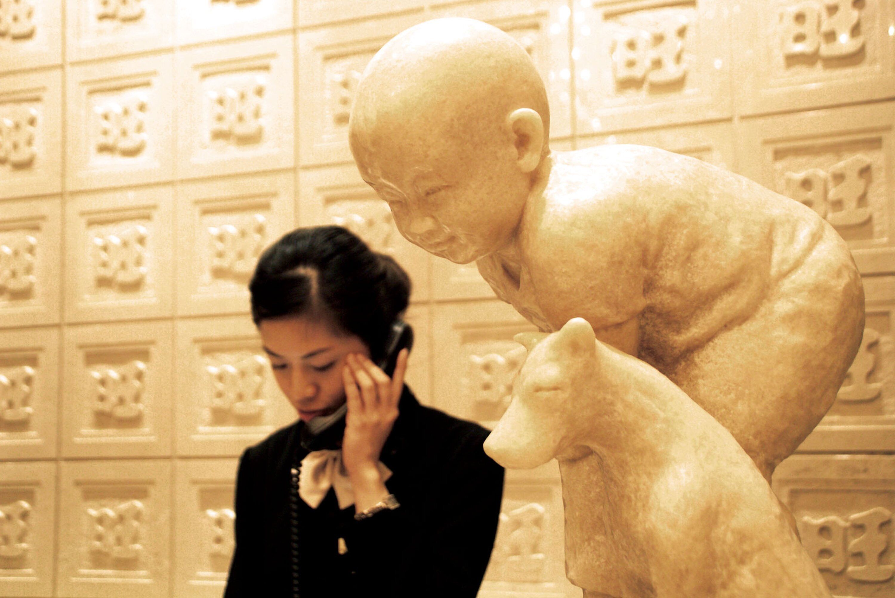 A person standing next to a sculpture of a child and an animal.