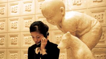 A person standing next to a sculpture of a child and an animal.