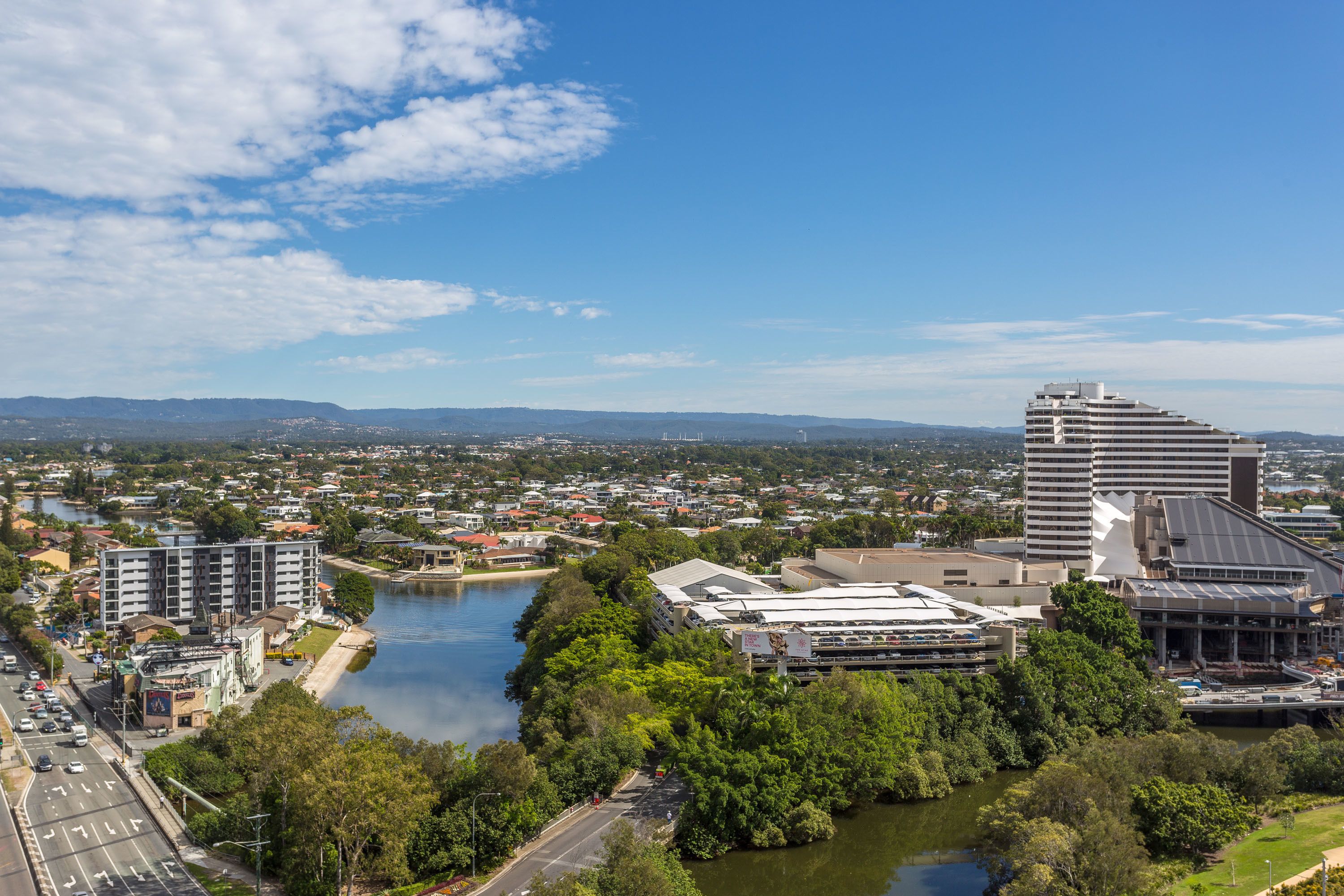 A cityscape with a river, modern buildings, and a large hotel with a unique architectural design.