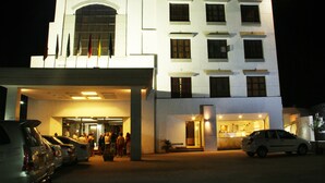 A hotel with a large entrance, multiple windows, and a parking area with several cars. - The Manor Hotel (Chhatrapati Sambhajinagar)