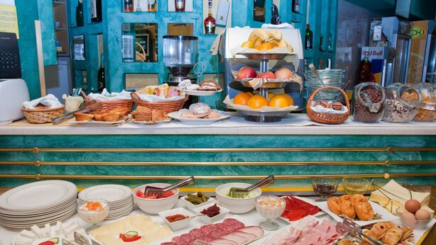Un buffet proposant une variété de plats, notamment des fruits, des viandes et des pâtisseries.