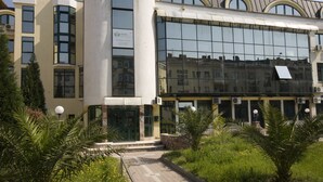 Un bâtiment moderne doté de grandes fenêtres, d’un toit incurvé et d’une enseigne indiquant qu’il s’agit d’une école.
