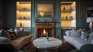 A cozy living room with a fireplace, two sofas, a round coffee table, and decorative shelves. - Cuillin Hills Hotel (Portree)