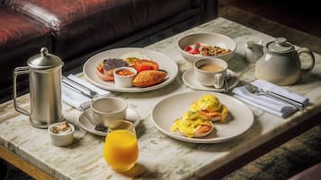 A breakfast setting with a coffee pot, teapot, and plates of food on a marble table.
