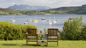 A lakeside view with boats, chairs, and a table. - Cuillin Hills Hotel (Portree)