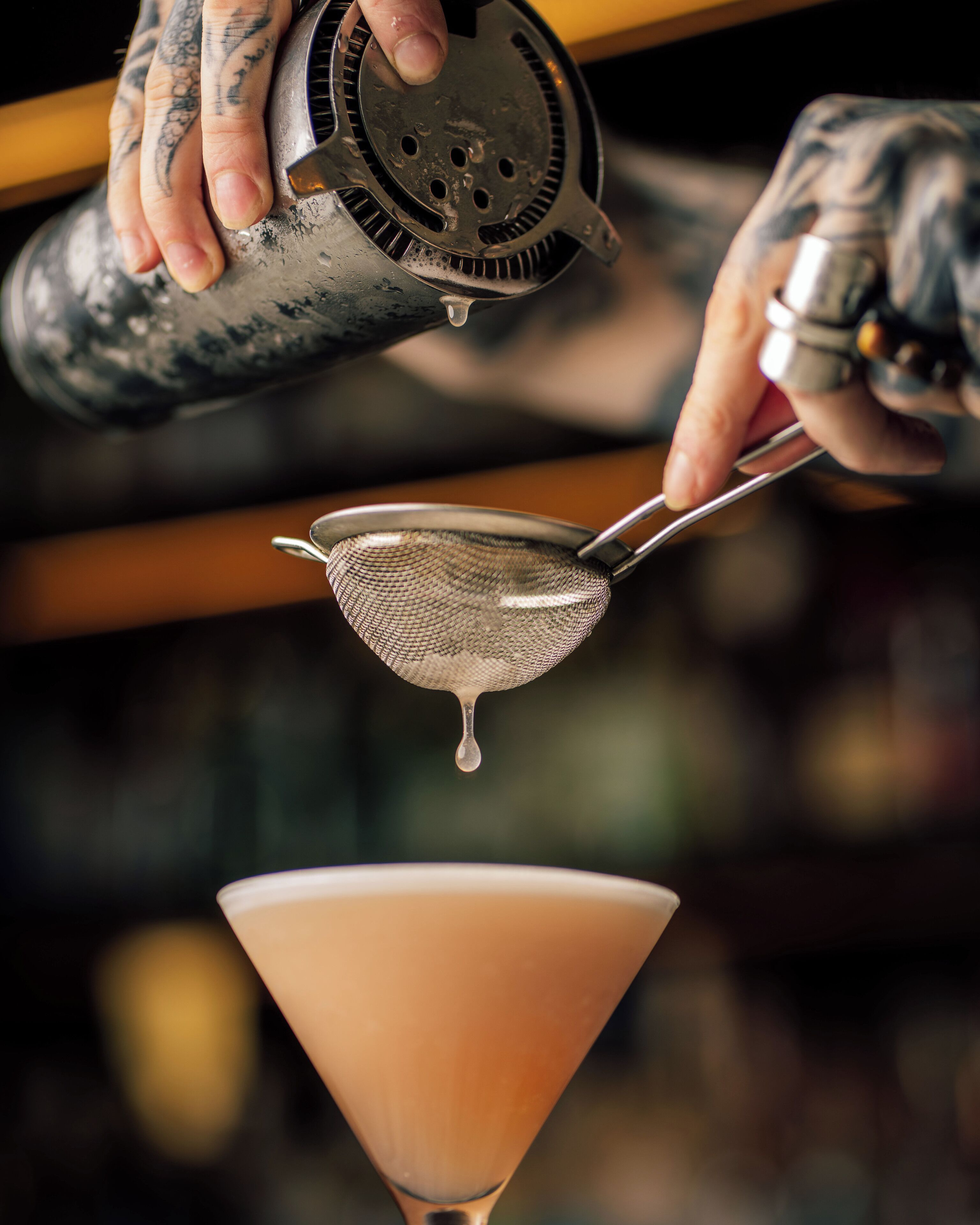 Un cantinero sirviendo una bebida en una copa de martini.