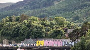 A coastal town with colorful buildings, a grassy area with benches, and boats on the water.