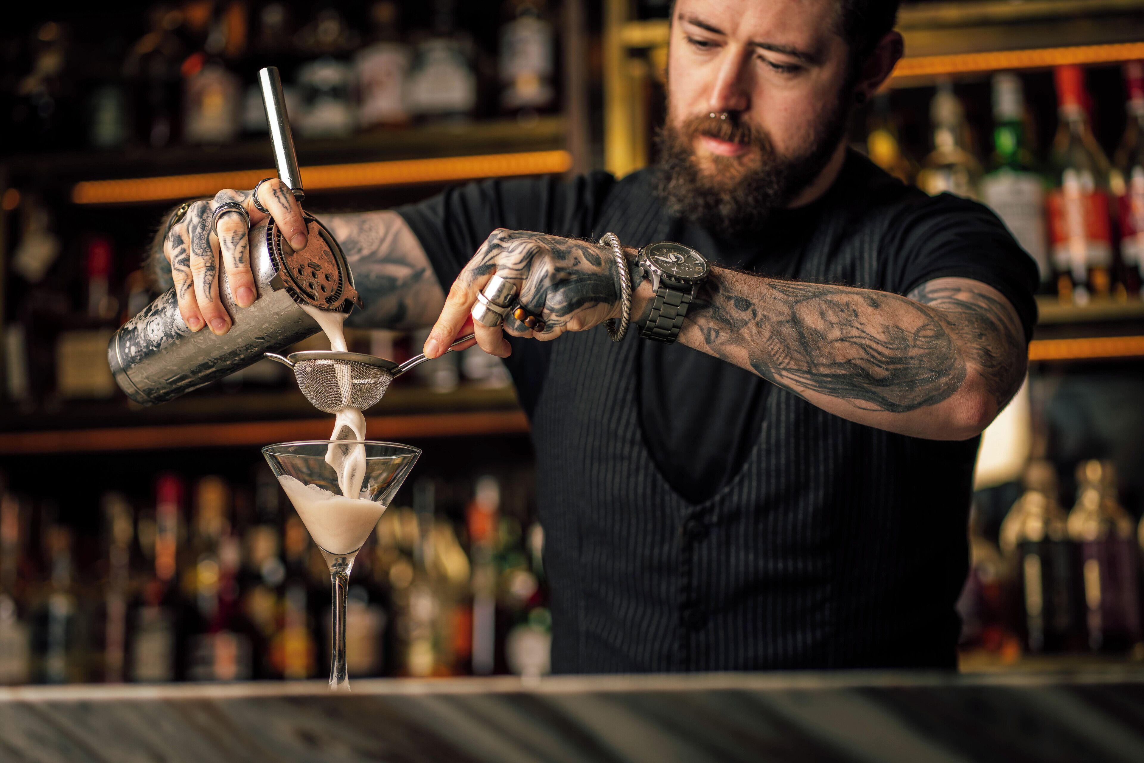Un barman verse une boisson dans un verre à martini.
