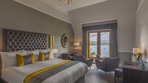 A hotel room with a large bed, a desk, and a view of the water. - Cuillin Hills Hotel (Portree)