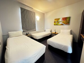 A hotel room with two single beds, a small table, a lamp, a painting on the wall, and a window with a blind. - Best Western Wellington (Wellington)