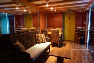 A room with wicker furniture, a wooden table, and a yellow door.