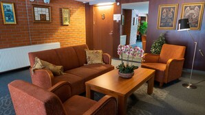 A hotel lobby with a brick wall, framed pictures, a wooden sofa, a wooden coffee table, and a floor lamp. - Tahetorni Hotel (Tallinn)