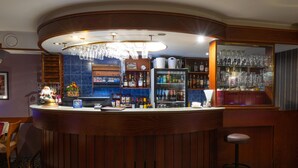 A bar area with a curved counter, a minibar, and a variety of bottles and glasses. - Tahetorni Hotel (Tallinn)
