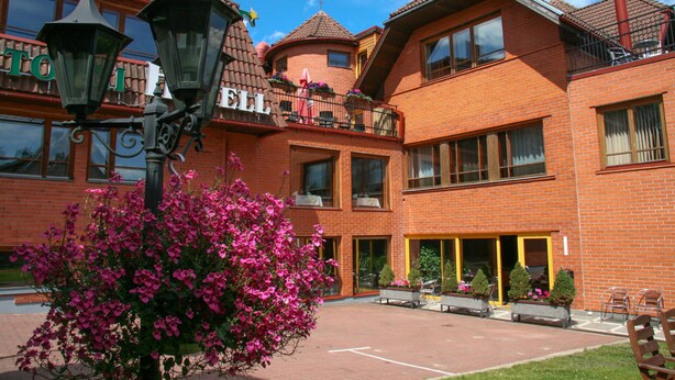 A red brick building with a balcony, large windows, and a flower bed. - Tahetorni Hotel (Tallinn)