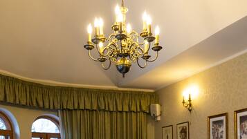 A conference room with a long table, chairs, a chandelier, and framed pictures on the wall.