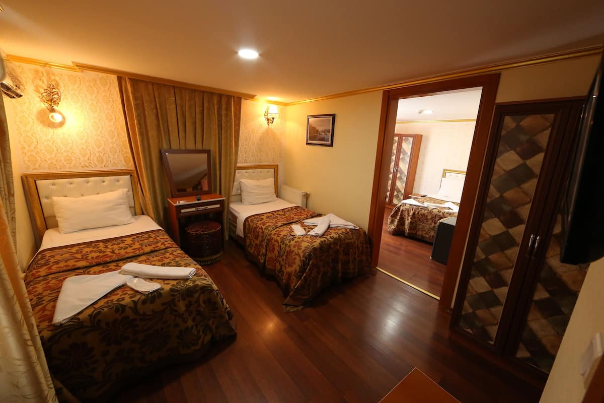 Quarto de hotel com duas camas, um espelho, uma televisão e um guarda-roupa.