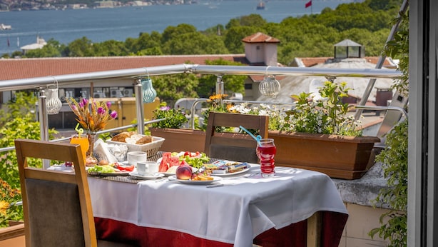 A dining table with a white tablecloth, set with plates of food, drinks, and a vase of flowers. - Meddusa Hotel (Istanbul)