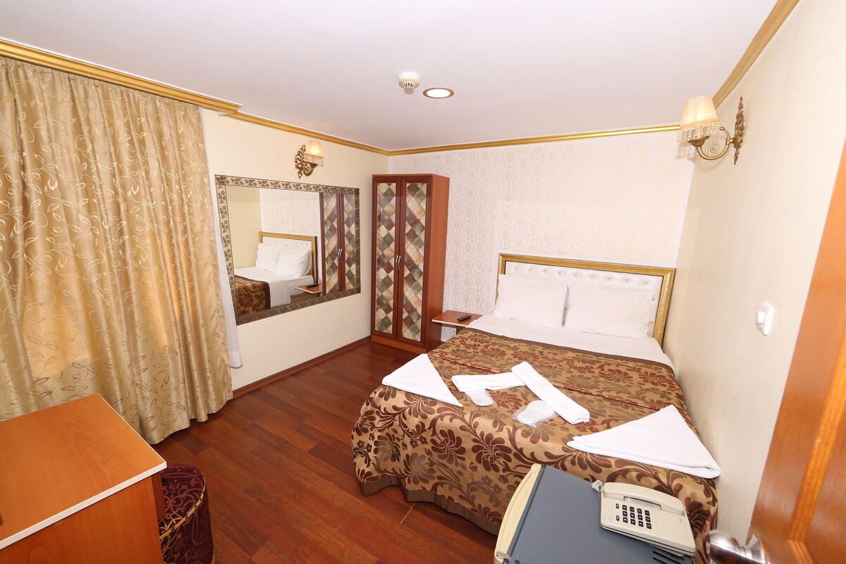 Una habitación de hotel con cama, escritorio, teléfono y espejo.