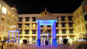 A hotel courtyard with a central gazebo, multiple seating areas, and a pool. - Cambay Grand (Amer)