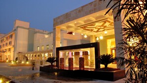 A hotel entrance with a modern design, featuring a water feature and a well-lit facade. - Cambay Grand (Amer)