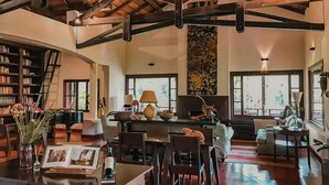 A spacious living area with a high ceiling, a fireplace, and a large window. - Posada Puerto Bemberg (Puerto Libertad)