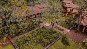 A traditional villa with a tiled roof, surrounded by lush greenery and a small courtyard. - Posada Puerto Bemberg (Puerto Libertad)