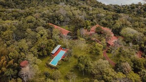 An aerial view of a property with a swimming pool, surrounded by dense forest and a river. - Posada Puerto Bemberg (Puerto Libertad)