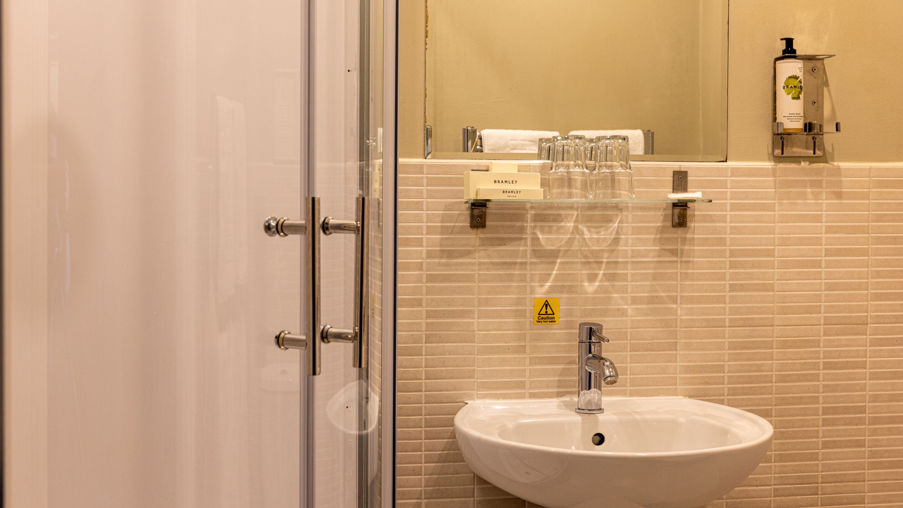 A bathroom with a white sink, a glass shower enclosure, and a mirror with a towel rack.