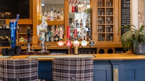 A bar area with multiple beer taps, a variety of liquor bottles, and a menu board. - The Plough (Alnwick)