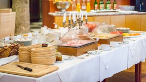 A buffet setup with various food items, a candelabra, and a fruit display. - Hotel Schloss Leonstain (Poertschach am Woerthersee)