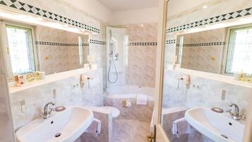 A modern bathroom with two sinks, a bathtub, and a shower.