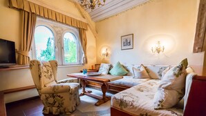A cozy living room with a sofa, armchair, and a wooden coffee table. - Hotel Schloss Leonstain (Poertschach am Woerthersee)